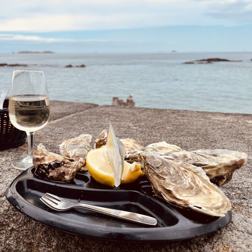 Austern und Weißwein vor auf den Klippen der Bretagne.