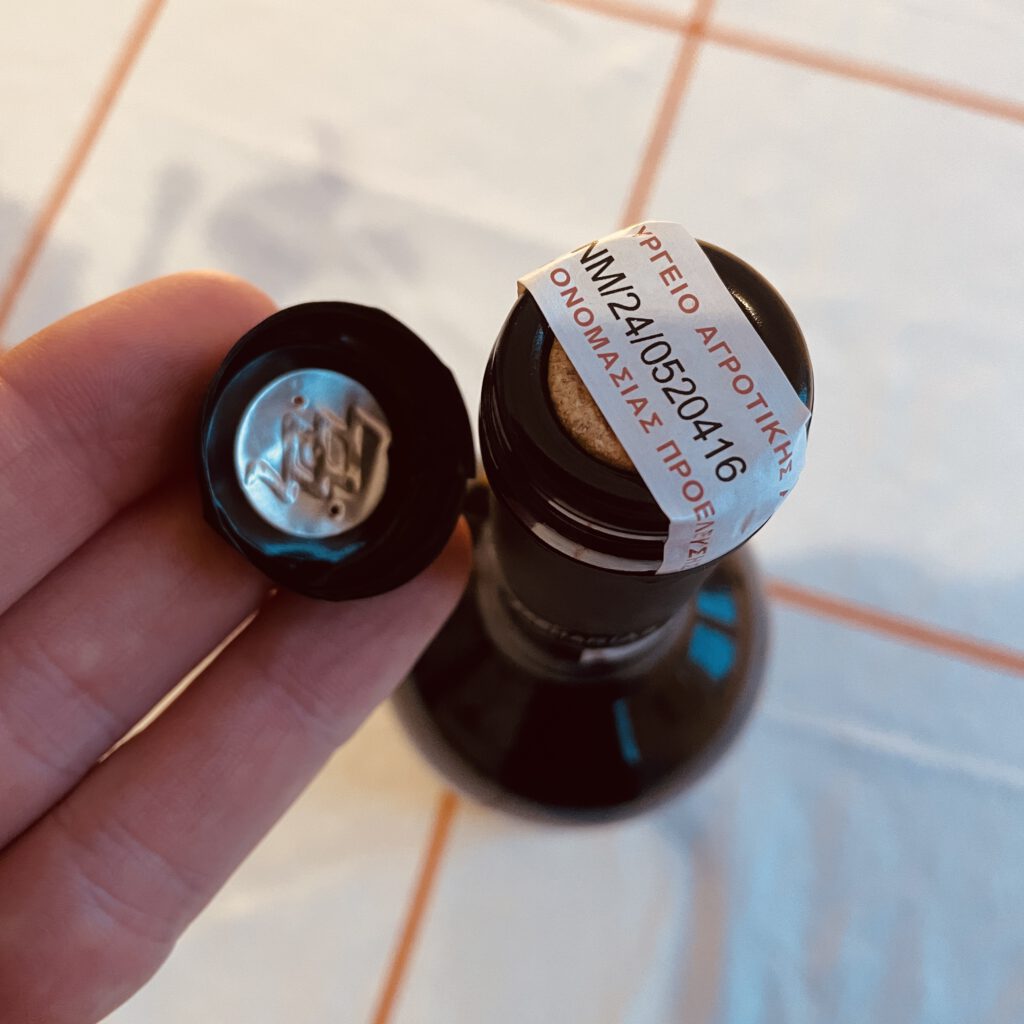 Eine Banderole auf den Korken, aber unter der Kapsel.