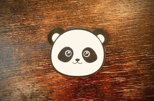 Ein stilisierter Panda-Kopf auf einem Holztisch.