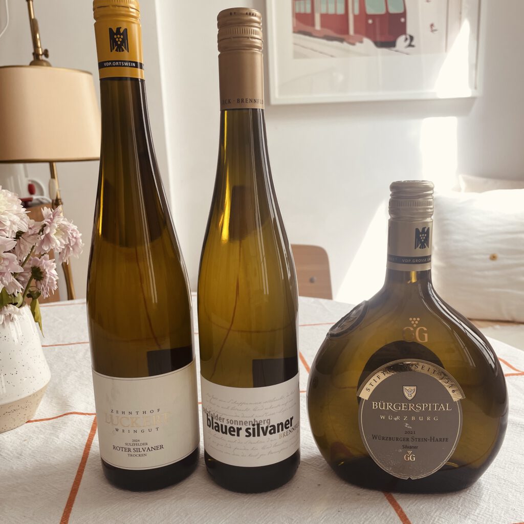 Ein roter, ein blauer und ein grüner Silvaner auf einem Küchenstich stehend.